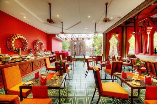 a restaurant with red walls and tables and chairs at Golden Temple Retreat in Siem Reap