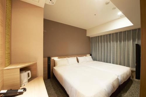 Un dormitorio con una cama blanca y un televisor. en Sotetsu Fresa Inn Tokyo Kanda, en Tokio