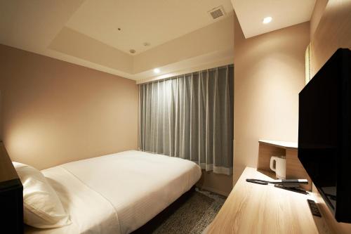 Una habitación de hotel con una cama y una ventana. en Sotetsu Fresa Inn Tokyo Kanda, en Tokio