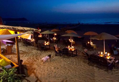un grupo de personas en la playa por la noche en Sealand Beach Cottages, en Patnem