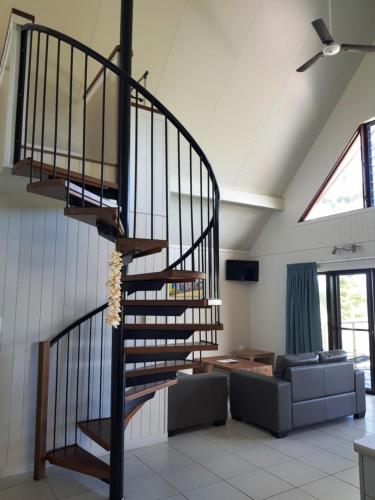 a spiral staircase in a living room with a couch at Cardwell Beachcomber Motel & Tourist Park in Cardwell
