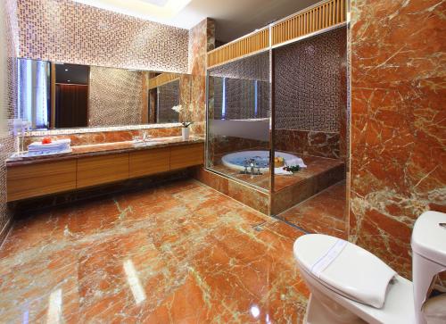 a bathroom with a tub and a toilet and a mirror at Spring Hotel in Taichung