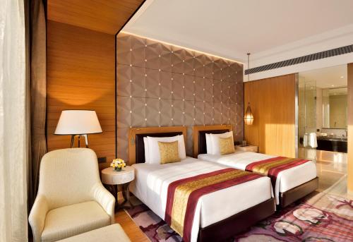 a hotel room with two beds and a chair at Radisson Blu Coimbatore in Coimbatore