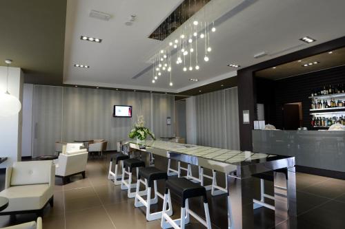 a restaurant with a bar and white chairs at Best Western Premier CHC Airport in Genova
