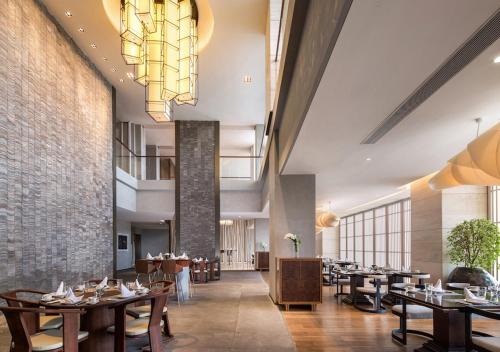 a restaurant with tables and chairs and a chandelier at The Mangrovetree Sanya Resort in Sanya