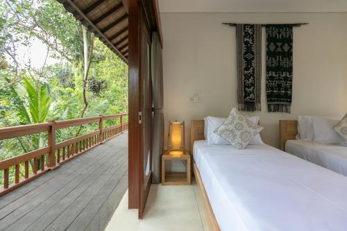 a room with two beds on a porch with a deck at Villa Sunari Ubud in Ubud