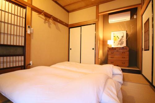 a bedroom with a white bed in a room at Hostel Fish in a River in Takayama
