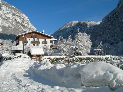 a house covered in snow with mountains in the background at Hotel Des Roses in Antey-Saint-André