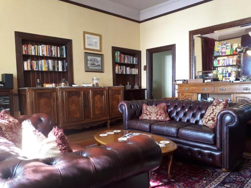 a living room with two leather couches and a table at Kurrara Historic Guest House in Katoomba