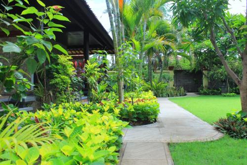 a garden with green plants and a walkway at Mans Cottages & Spa in Pemuteran