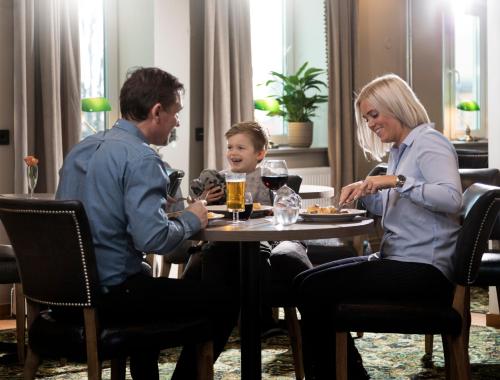 two adults and a child sitting at a table at Hotell Nordic in Norrköping