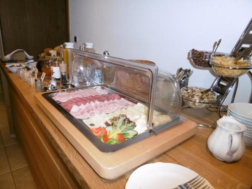 ein Buffet mit Fleisch und Gemüse in einem Glasbehälter in der Unterkunft Gästepension zum Stern in Bühlertann