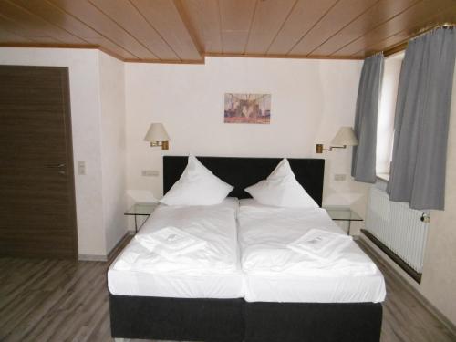 Bühlertann的住宿－Gästepension zum Stern，一间卧室配有一张带白色床单的大床