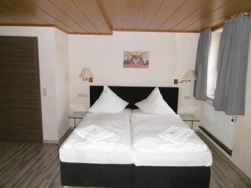 a bedroom with a large bed with white sheets at Gästepension zum Stern in Bühlertann