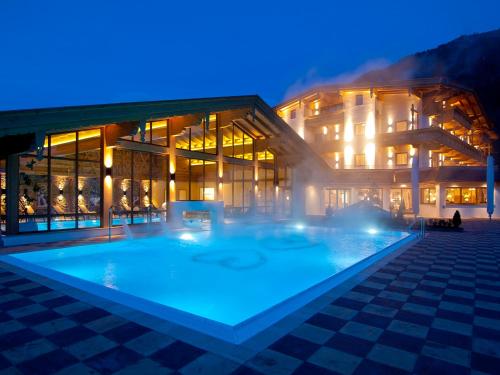 un edificio con una gran piscina frente a él en Hotel Wöscherhof - 4 Sterne Superior en Uderns
