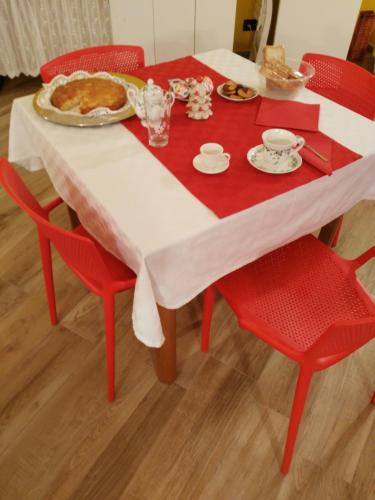 a table with red chairs and a plate of food on it at La Corte B&B in Candiolo
