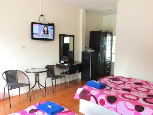 1 dormitorio con cama, mesa y TV en Purinplace, en Pluak Daeng