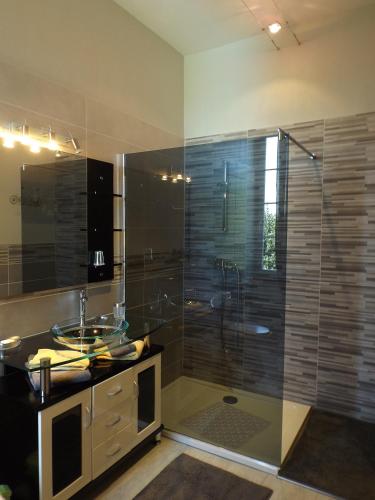 La salle de bains est pourvue d'une douche en verre, d'un lavabo et d'une baignoire. dans l'établissement Relais de l'Alaric, à Moux