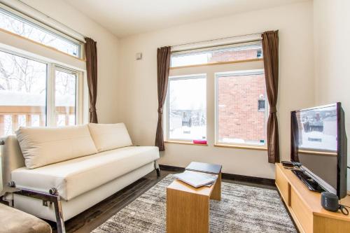 a living room with a couch and a tv at Lodge Mori Apartments in Niseko