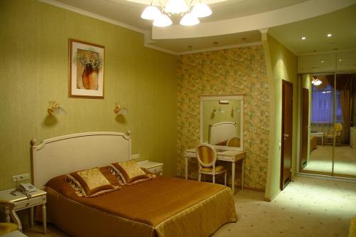 1 dormitorio con cama, mesa y espejo en Oazis Hotel, en Saratov
