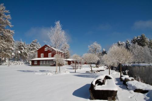 a red barn in the snow next to a lake at THE LODGE Torsby in Torsby