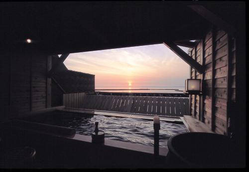 a bath tub with a view of the ocean at sunset at Sumiyoshiya in Nagaoka