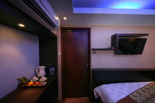 a room with a bed and a door with a television at Sari Gili Bungalow in Gili Air