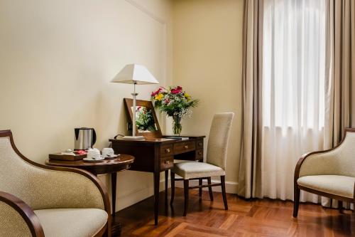 a room with a desk with chairs and a vase of flowers at Eurostars Centrale Palace Hotel in Palermo