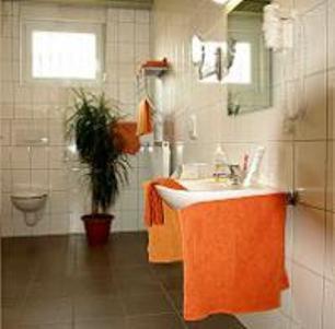 ein orangefarbenes Badezimmer mit einem Waschbecken und einem WC in der Unterkunft Econo Motel Goelzer in Büchenbeuren