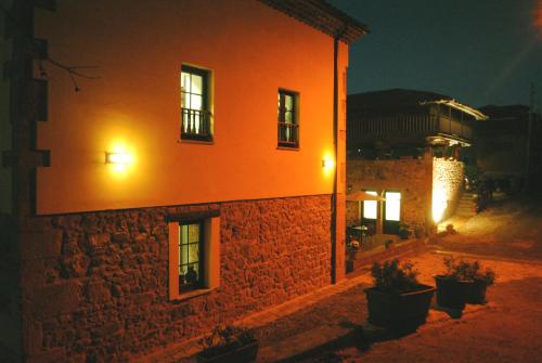 an orange building at night with plants in front of it at El Lacayo de Sestiello in Grado
