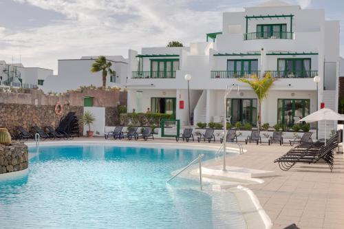 a hotel with a swimming pool in front of a building at Apartamentos El Guarapo in Costa Teguise