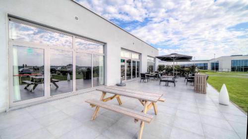 a patio with a bench and tables and windows at Hotel-Restaurant Horizon Ath-Lessines in Ghislenghien