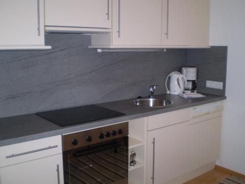 a kitchen with white cabinets and a sink at Apart Hotel Garni Strasser in Zell am Ziller
