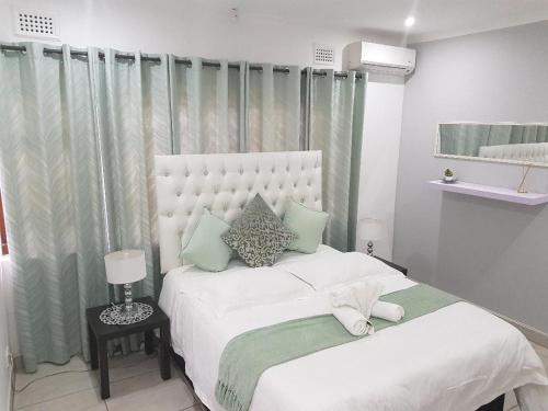 a bedroom with two beds with white sheets and green pillows at The Grand Orchid Guesthouse in Durban
