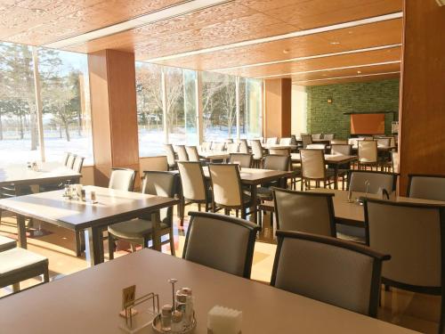a restaurant with tables and chairs and a large window at Hotel Tetoraresort Tokachigawa in Otofuke