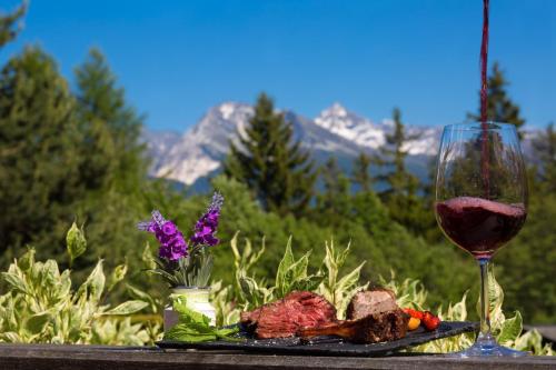 a plate of meat and a glass of wine on a table at Hotel La Prairie in Crans-Montana