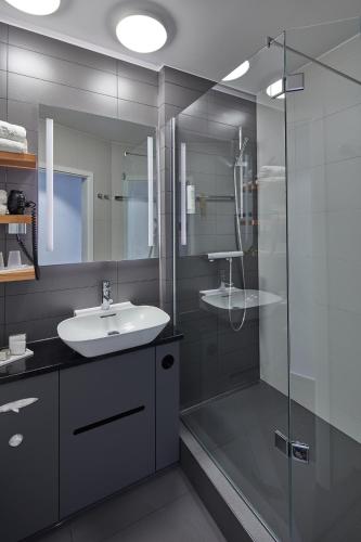 a bathroom with a sink and a glass shower at Landhotel Naafs-Häuschen in Lohmar