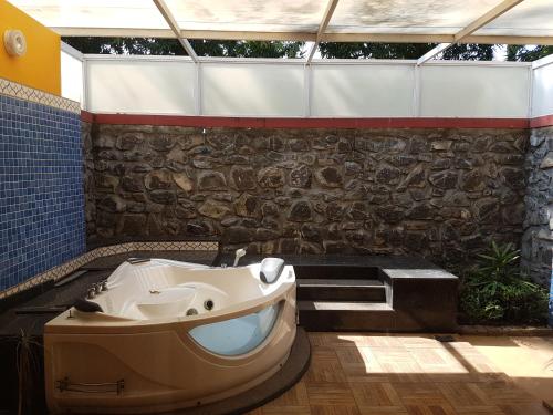 a bathroom with a tub and a stone wall at Vgp Golden Beach Resort in Chennai