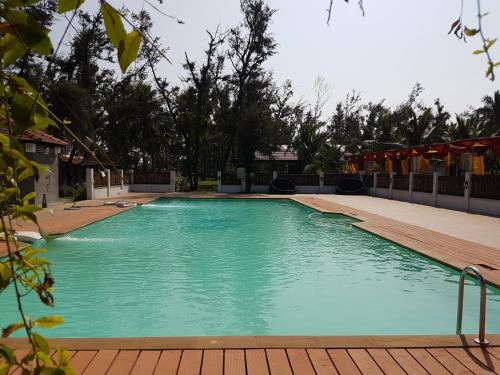 a large blue swimming pool with a wooden deck at Vgp Golden Beach Resort in Chennai