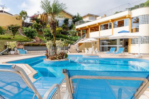 a swimming pool with two chairs and a house at Pousada Homestay Jaraguá Do Sul in Jaraguá do Sul