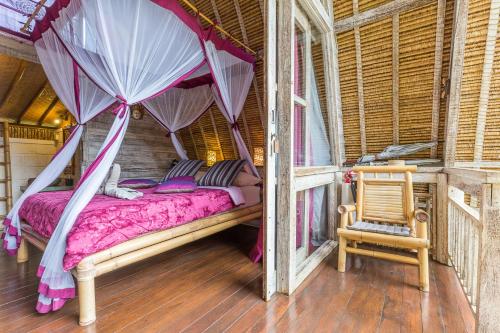 a bedroom with a canopy bed and a chair at Milo's Home in Jimbaran