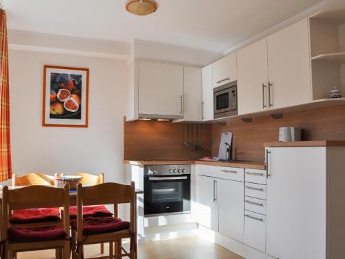 a kitchen with white cabinets and a table and chairs at Haus am Deich in Utersum