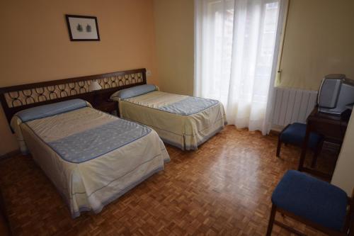 a room with two beds and a tv and a television at Hostal Blazquez Sanchez in Béjar