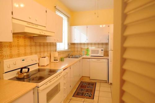 a kitchen with a sink, stove, cabinets and a window at Bay View Suites Paradise Island in Nassau