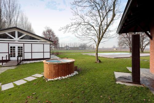 a building with a tree and a tub in the grass at Agriturismo Tenuta "Il Cigno" in Villanterio