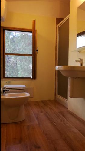 a bathroom with a sink and a toilet and a window at Camping Bella Sardinia in S'archittu Cuglieri