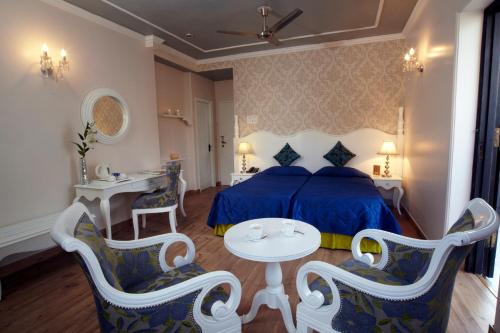 a bedroom with a blue bed and a table and chairs at Hotel Ajanta - Colonial Charm Award Winning Luxury Hotel in the Heart of the City in New Delhi