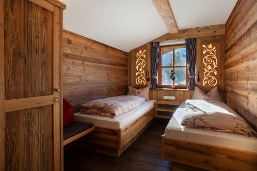 two beds in a room with wooden walls at Apartments Haus am Anger - Romantik-Beauty-Wellness in Jungholz