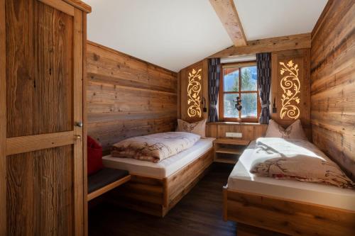 two beds in a room with wooden walls at Alpinrefugium Haus am Anger in Jungholz
