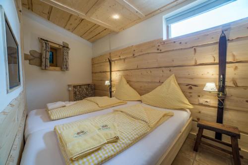 two beds in a room with a wooden wall at Apartments Landhaus Sonnheim in Lofer